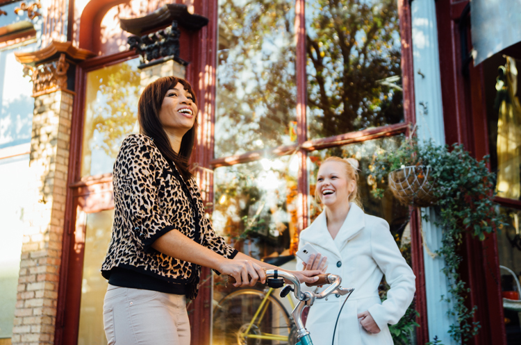 Woman with bike talking to other woman on sidewalk