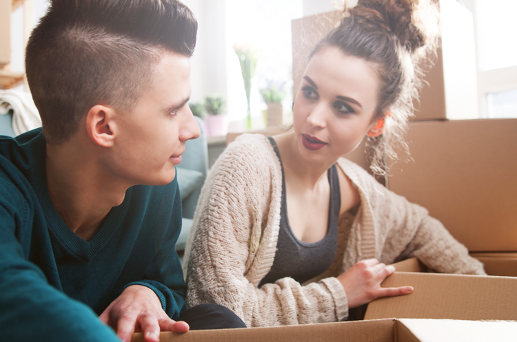 Two people looking at each other while packing boxes