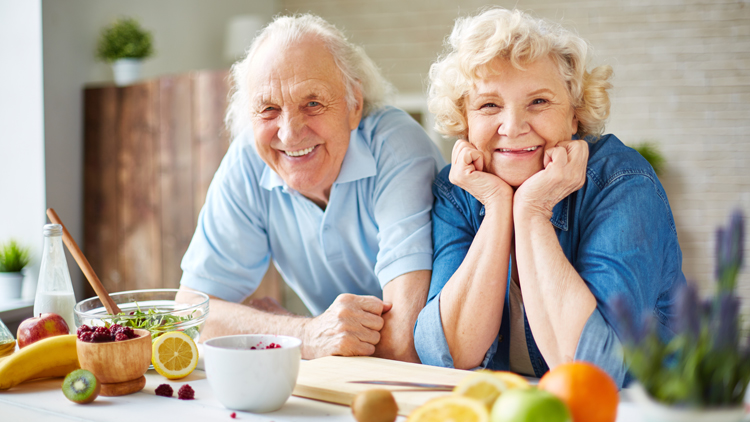 Two elderly people at a counter with food on it