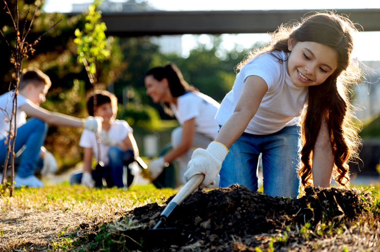 Kid digging a hole with a trowel for a tree