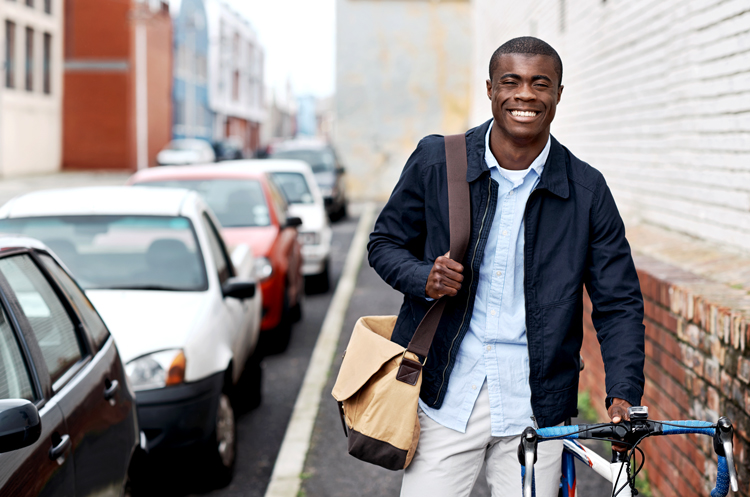 Man walking a bike on a city sidewalk