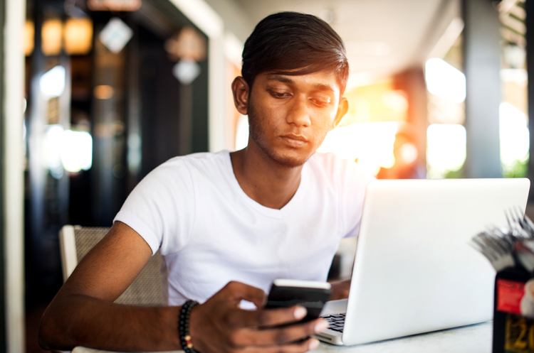 Young man sitting at table looking at cell phone