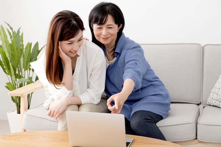 Woman points at laptop screen while chatting with another woman