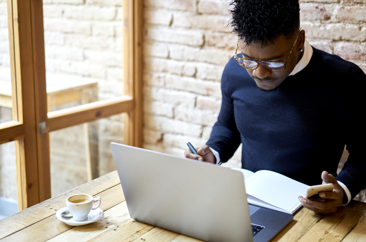 Man sits at table looking at laptop screen