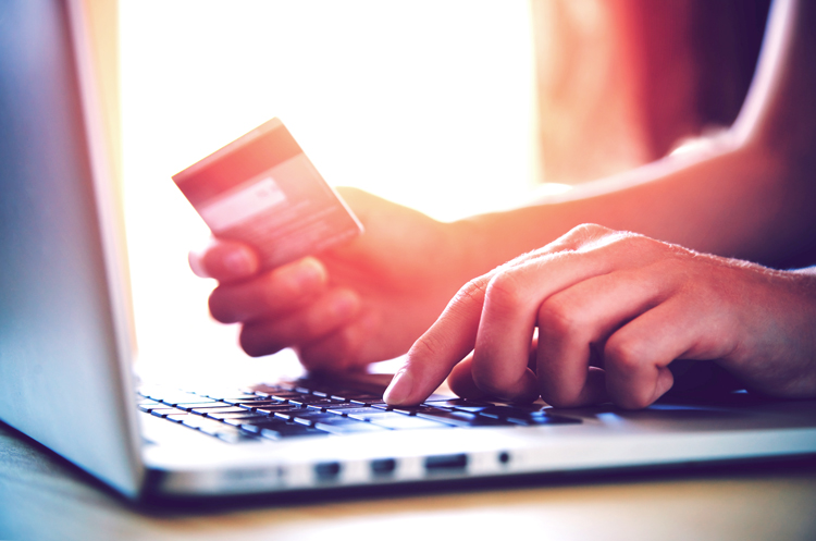 Person on laptop holding a credit card