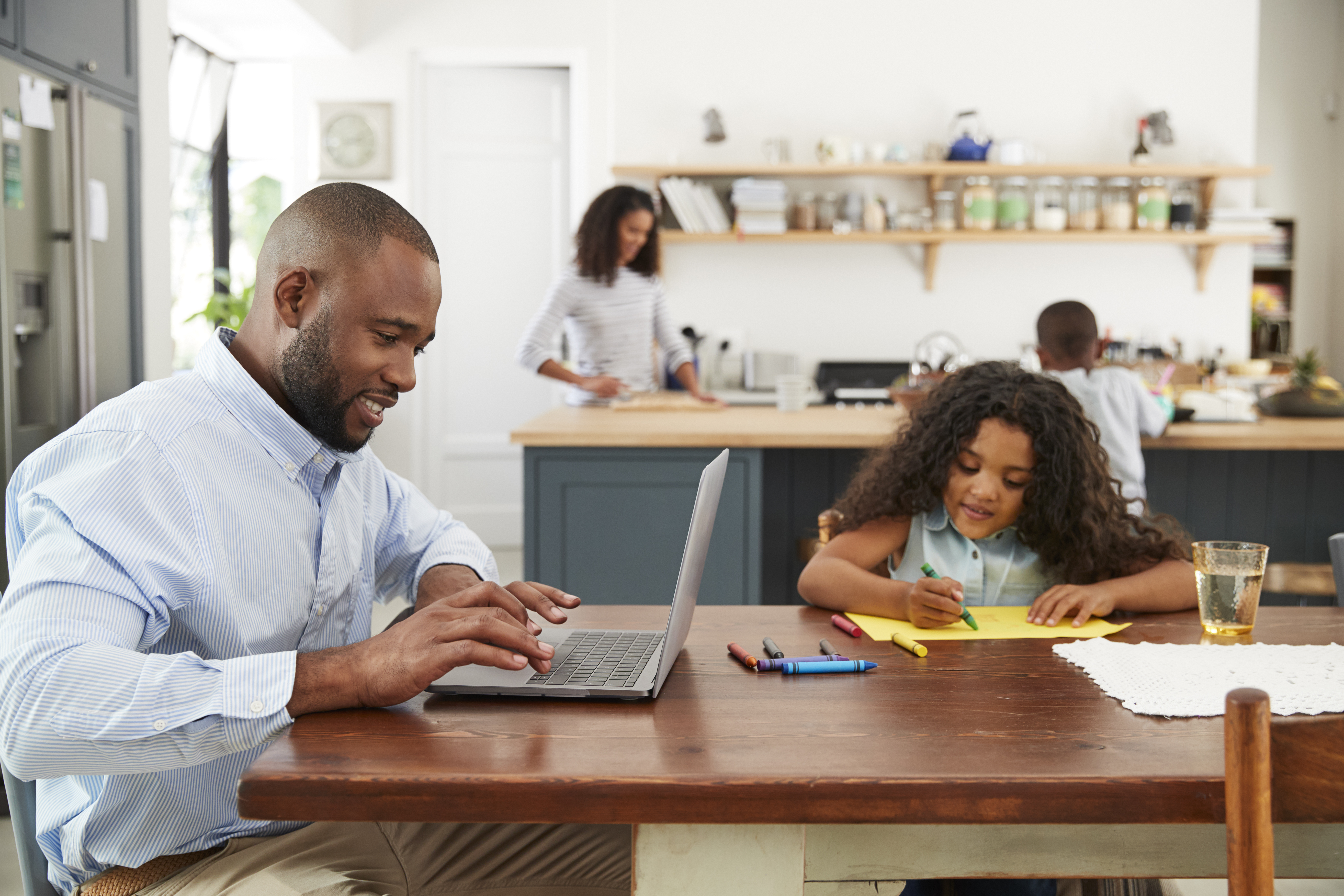 Man working at laptop with family in kitchen