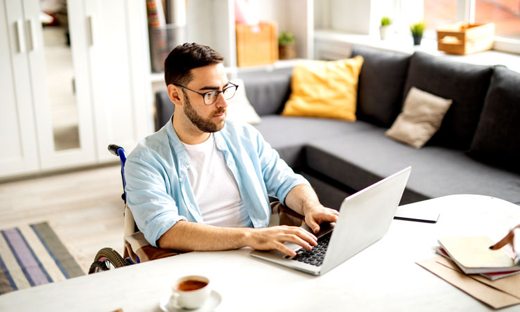 Man in wheelchair works on laptop